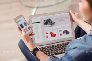 ホームページの制作や運用をイメージした画像。ノートPCとスマートフォンの画面にネット通販サイトが表示されている。